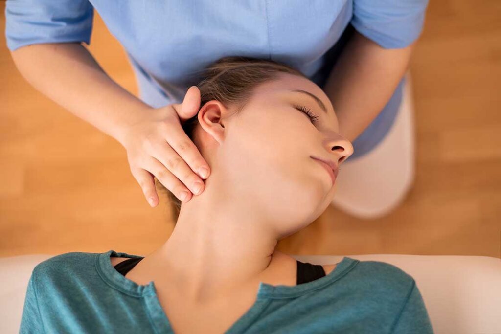 A chiropractor performing a spinal adjustment while another person receives a massage on a table nearby.