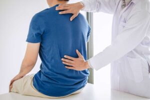 A chiropractor gently adjusting an adult client's neck with natural light in a calm treatment room.