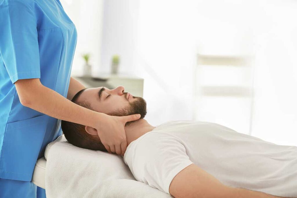 A person pressing on their upper back with a hand, showing discomfort from a muscle knot.