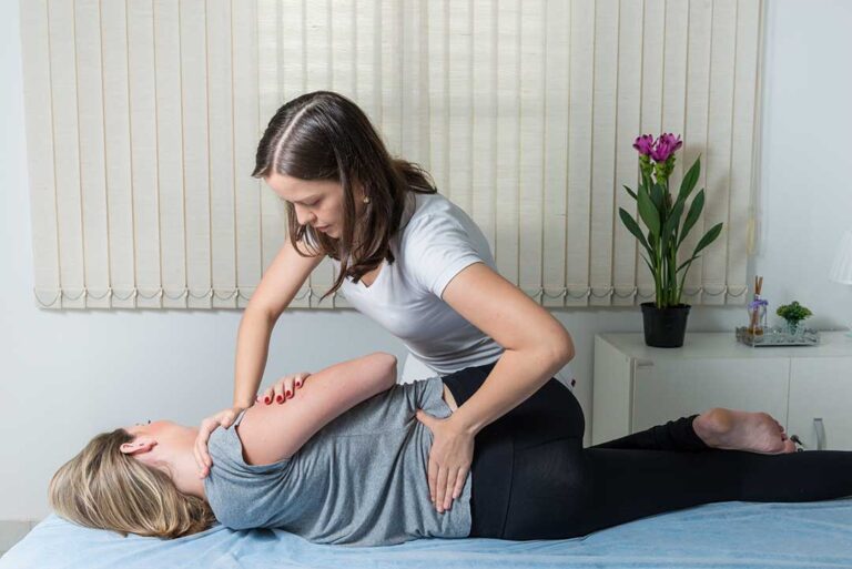 Practitioner reviewing a patient’s health history before a gentle spinal mobility assessment